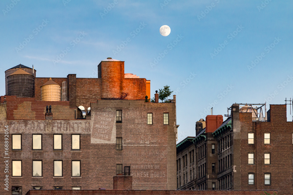Full moon rising above old brick buildings around Union Square Park in Manhattan, New York City