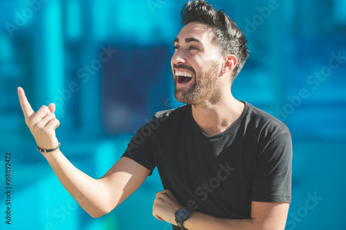 Young happy man pointing up laughing