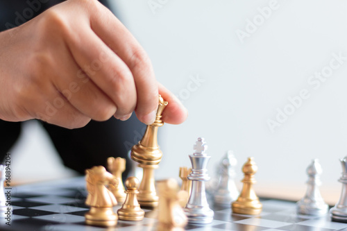 Close up shot hand of business woman moving golden chess to defeat a silver king chess on white and black chess board for business challenge competition winner and loser concept