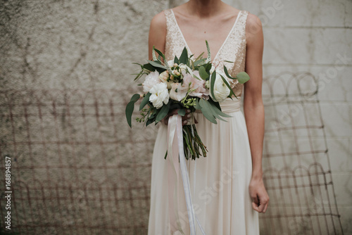 Bohemian indie bride in simple sparkle top wedding dress and feminine pastel bouquet with ribbon