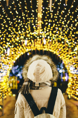 Back view of woman with backpack standing under illuminated garl photo