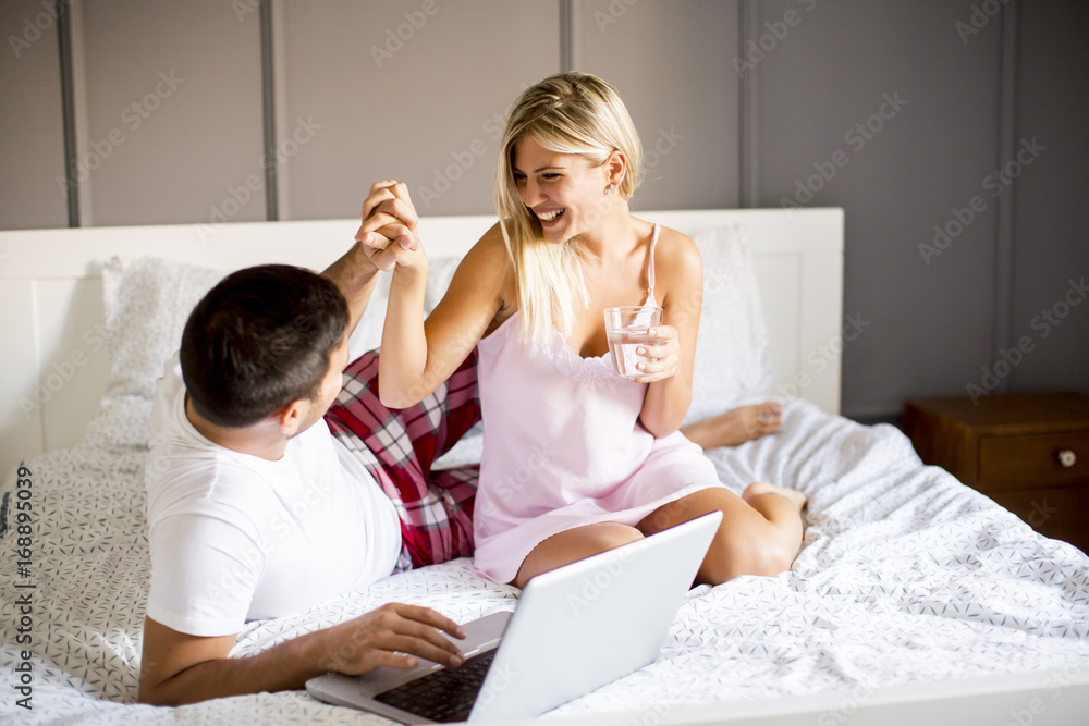 Intimate lovers using laptop lying on the bed Intimate lovers using laptop lying on the bed
