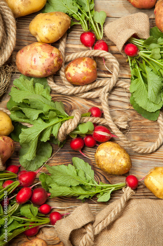 Potatoes and radishes on a wooden background
