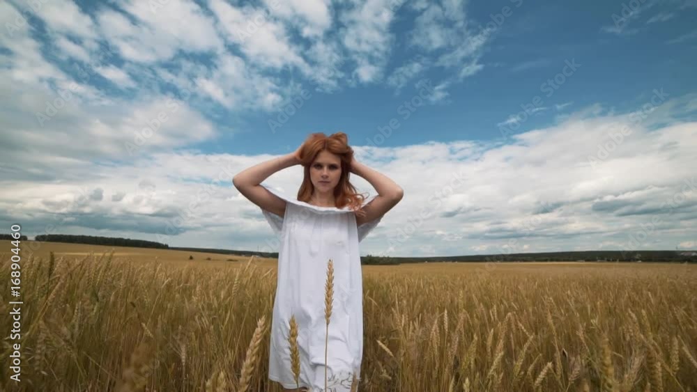 red-haired girl in a field of wheat in a white dress smiles a lovely smile , a perfect picture for advertising in the style lifestyle