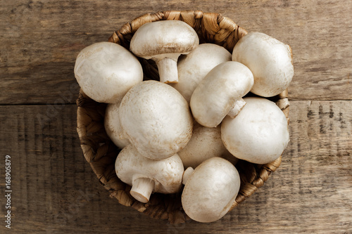 Mushrooms champignons in a wicker basket on a wooden background