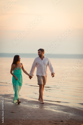 Enamored spouses stroll along the beach near the river, they walk in the nature