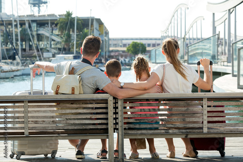 Back view of husband with wife and children who are sitting on bench © JackF