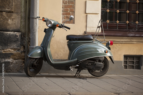 Motor scooters, parked in front of the building wall