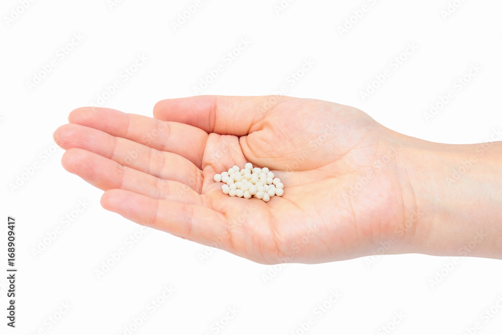 Hand holding homeopathic pills isolated on white background