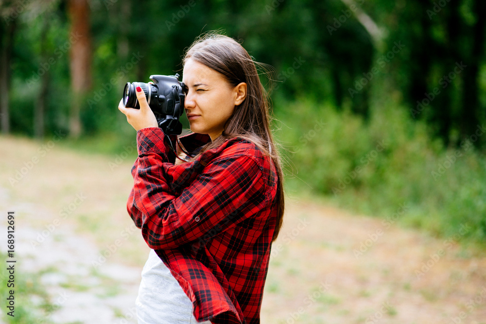White girl wearing plaid shirt holding camera in the forest White girl wearing plaid shirt holding camera in the forest