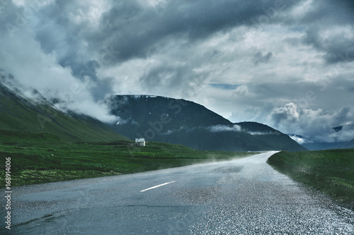 Travel to Iceland. A mountain road with fog to the town of Isafjordur and a view of the fjord after rain. focus on the road