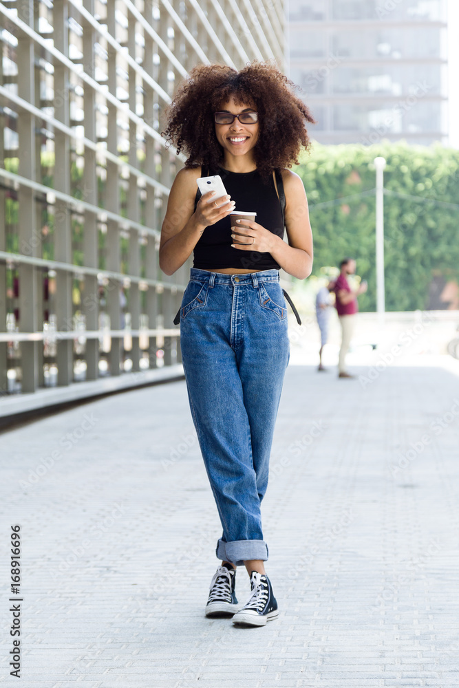 Beautiful young woman using her mobile phone in the street.