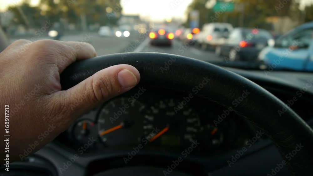 Driving at Sunset on the freeway. Traffic Jam. -Hand on steering wheel close up. POV. Driving at Sunset on the freeway. Traffic Jam. -Hand on steering wheel close up. POV.