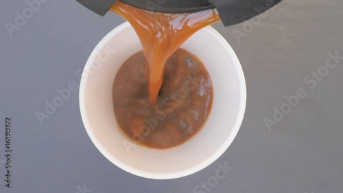 Coffee and milk pouring into paper cup, hand takes cup away, , slow motion