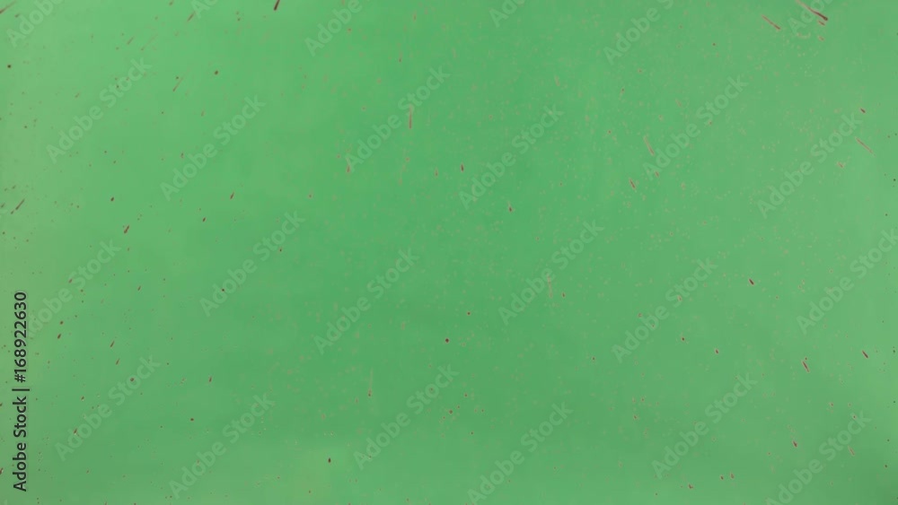 Red ink sprinkled over green screen background. Close-up shot Red ink sprinkled over green screen background. Close-up shot