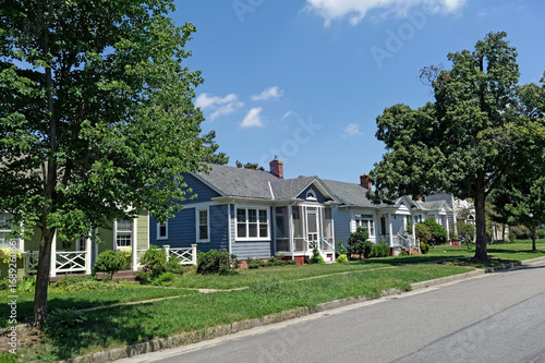 Residential city block with trees, blue sky and older modest working class homes. Nobody.