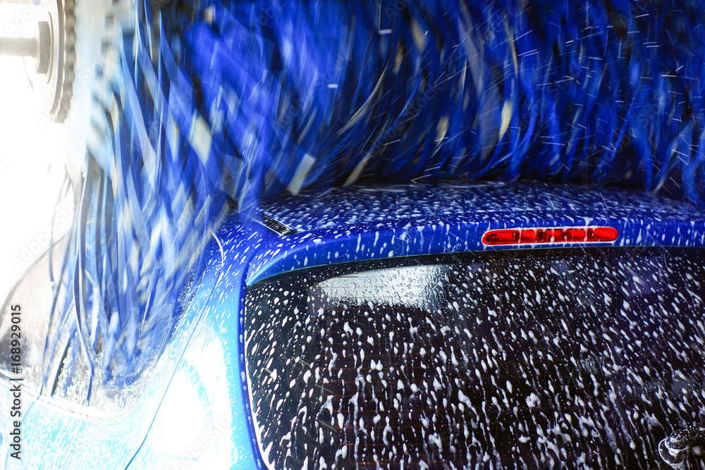 Car wash, black car in automatic car wash, rotating red and blue brush