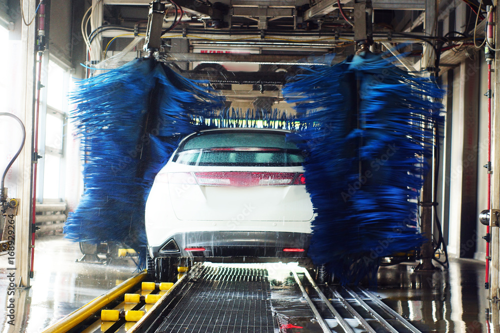 Obraz premium Car wash, black car in automatic car wash, rotating red and blue brush. Washing vehicle.