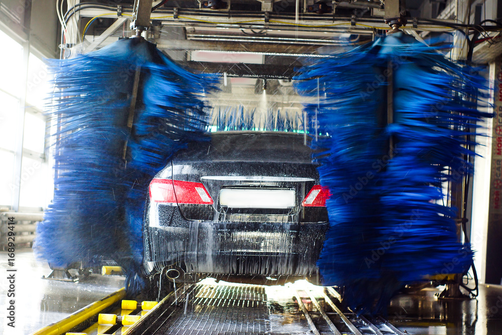 Car wash, black car in automatic car wash, rotating red and blue brush