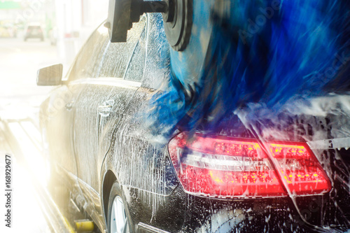 Car wash, black car in automatic car wash, rotating red and blue brush. Washing vehicle. photo