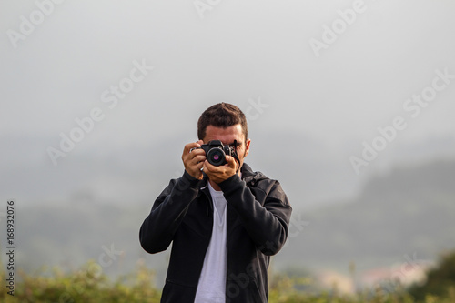 Front view of brunet man taking photo