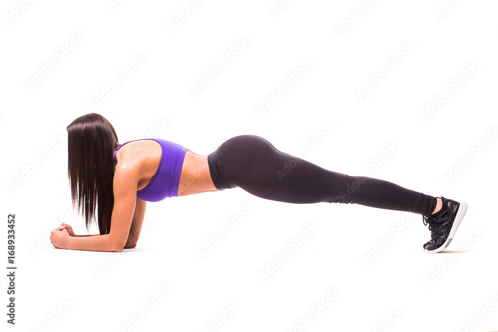 Concentrated beautiful fitness girl in sportwear exercising doing a plank over white background Concentrated beautiful fitness girl in sportwear exercising doing a plank over white background