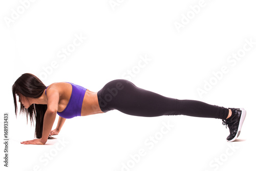 Concentrated beautiful fitness girl in sportwear exercising doing a plank over white background