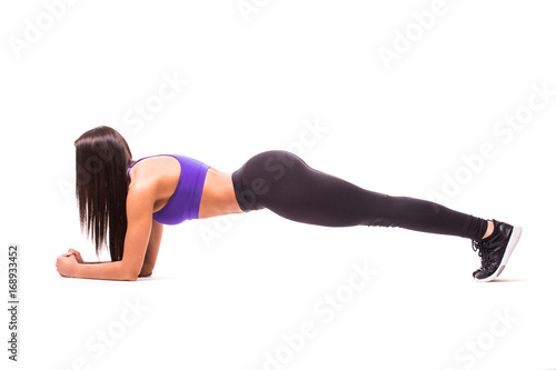 Concentrated beautiful fitness girl in sportwear exercising doing a plank over white background