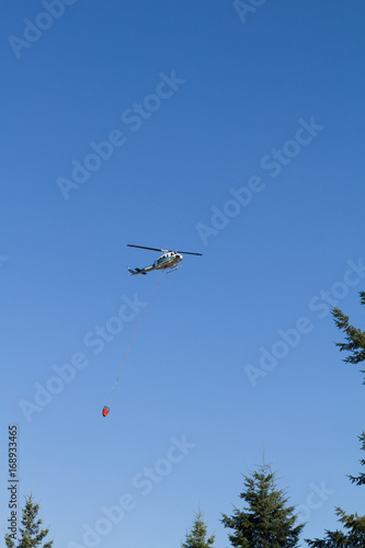 Aerial firefighting with helicopter carrying water bucket