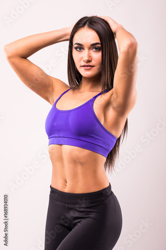 Smiling sports woman standing with arms over head and looking at camera isolated on a white background