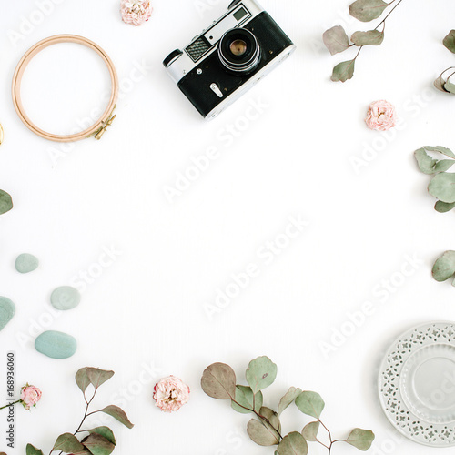 Flat lay border frame with retro camera, eucalyptus branches, plate on white background. Top view artist background with space for text.