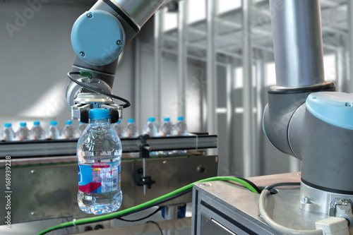 Automatic manufacturing production machine , robot gripper warehouse picking holding water bottle in smart factory. photo