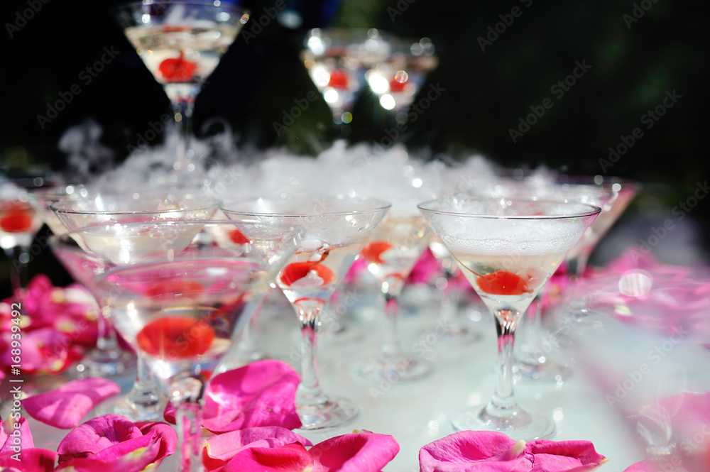 A slide of champagne with dry ice and smoke at the solemn event. Pyramid of glasses with alcohol and cherries. A slide of champagne with dry ice and smoke at the solemn event. Pyramid of glasses with alcohol and cherries.