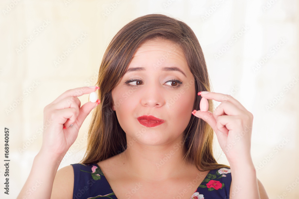 Portrait of a confused woman holding in both hands a soft gelatin vaginal tablet or suppository, treatment of diseases of the reproductive organs of women and prevention of women's health, in a Portrait of a confused woman holding in both hands a soft gelatin vaginal tablet or suppository, treatment of diseases of the reproductive organs of women and prevention of women's health, in a