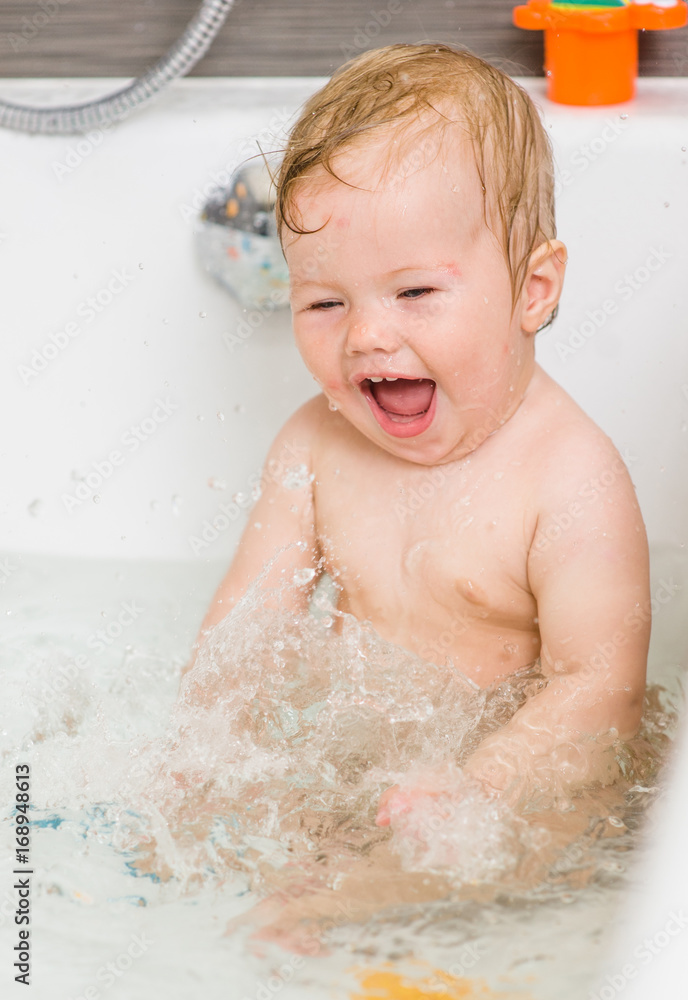 Laughing girl splashing in the water in the bathtub Laughing girl splashing in the water in the bathtub