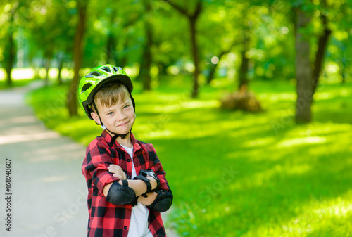 Portrait of a boy with arms crossed in a protective helmet and protective pads for roller skating