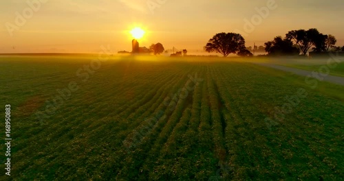 Ethereal, beautiful sunrise over foggy agricultural landscape, aerial perspective.
