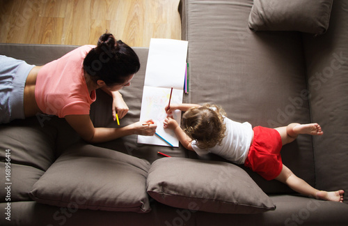 Mother lies on the couch with her daughter and draws photo