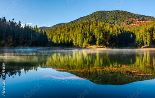 smokey lake reflect forest mountain and blue sky
