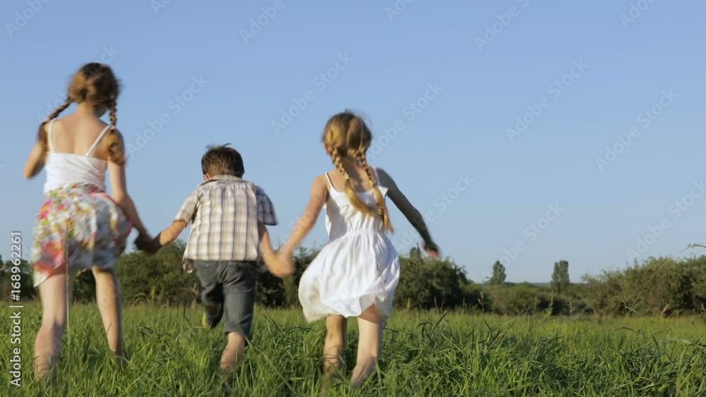 Three happy children playing in the field at the day time. Kid having fun outdoors. Concept of happy game. Three happy children playing in the field at the day time. Kid having fun outdoors. Concept of happy game.