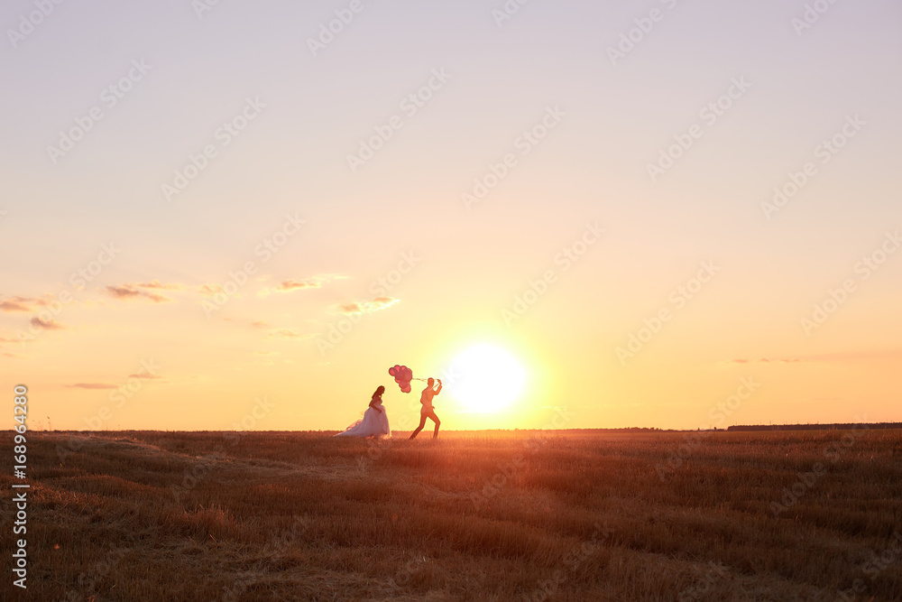 Bride and groom in a field at sunset with balloon
