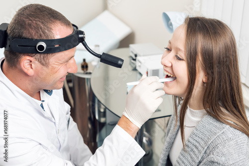 Doctor ENT checking ear with otoscope to woman patient. private clinic. otolaryngologist