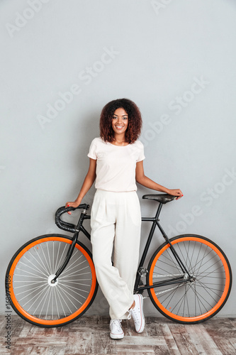 Vertical image of smiling african woman posing with bicycle © Drobot Dean