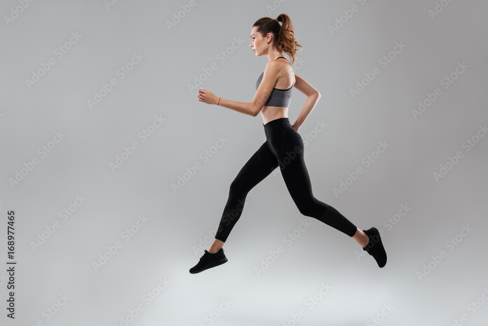 Side view full length portrait of a young sportswoman running Side view full length portrait of a young sportswoman running