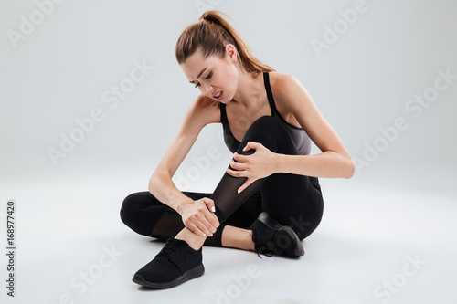 Young fitness woman suffering from an ankle pain