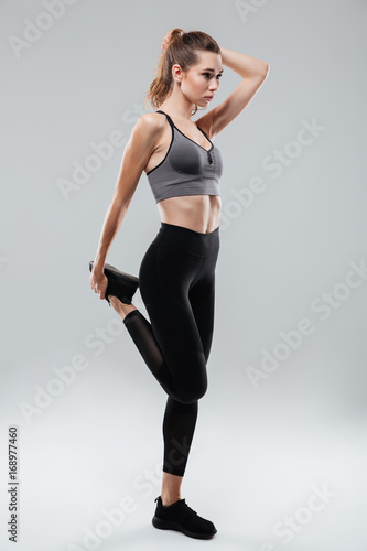 Portrait of a young fitness woman stretching leg while standing
