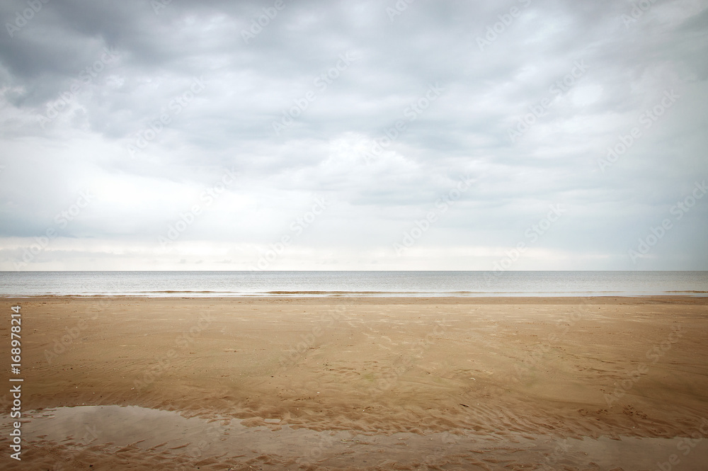 Calm beach landscape in fall in pastel colors. Serene autumn scene resembling minimalism painting in light blue and beige tones. No people. Horizon on the lower third. Space for text or motivation. Calm beach landscape in fall in pastel colors. Serene autumn scene resembling minimalism painting in light blue and beige tones. No people. Horizon on the lower third. Space for text or motivation.
