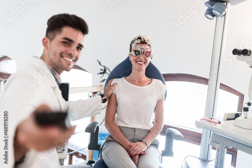 Tableau sur toile Male handsome optometrist checking patient's vision at eye clinic