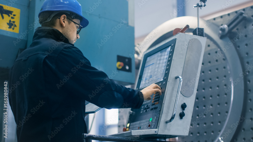 Factory worker is programming a CNC milling machine with a tablet computer. Factory worker is programming a CNC milling machine with a tablet computer.