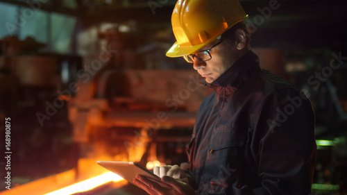 Engineer in Glasses using Tablet PC in Foundry. Industrial Environment.